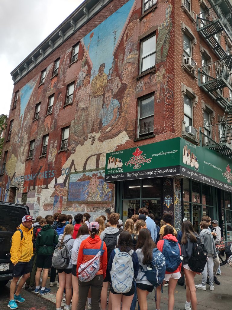 Tour group exploring East Harlem street mural and fragrance shop on Lexington Ave
