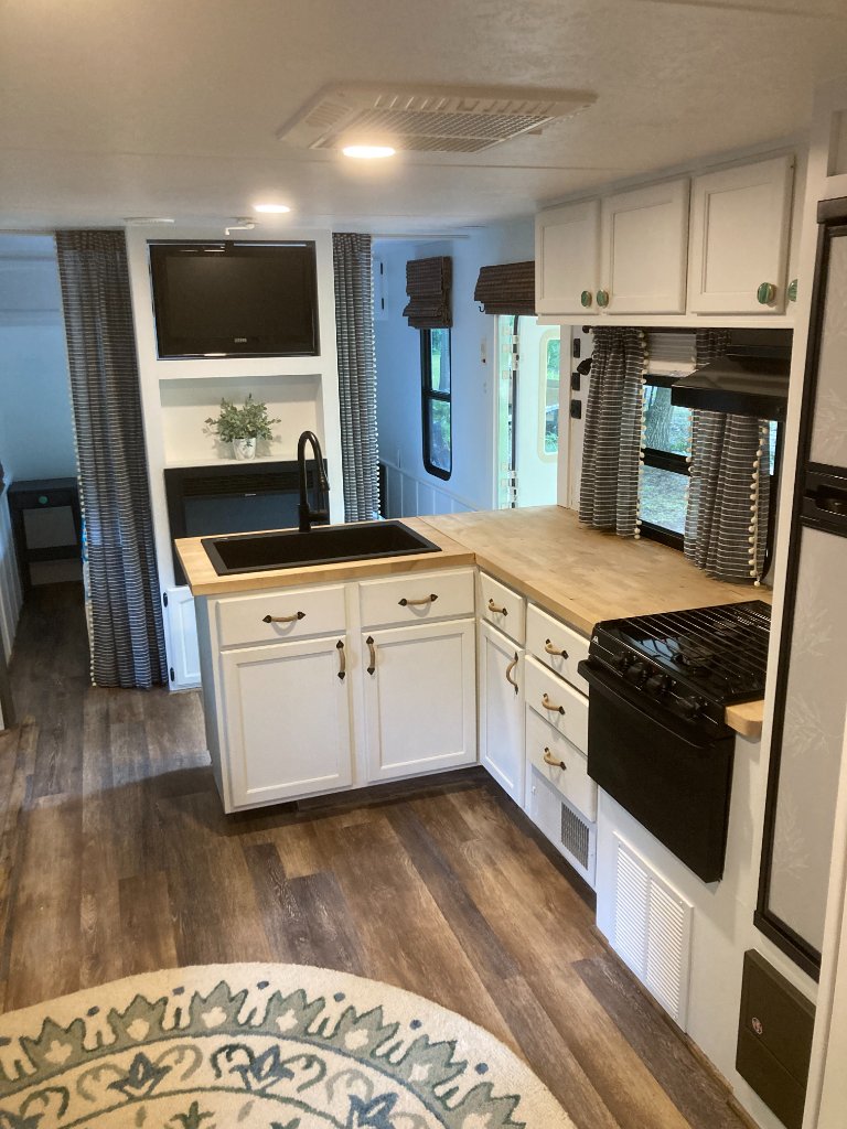 Hideout modern kitchen with white cabinets and entertainment center