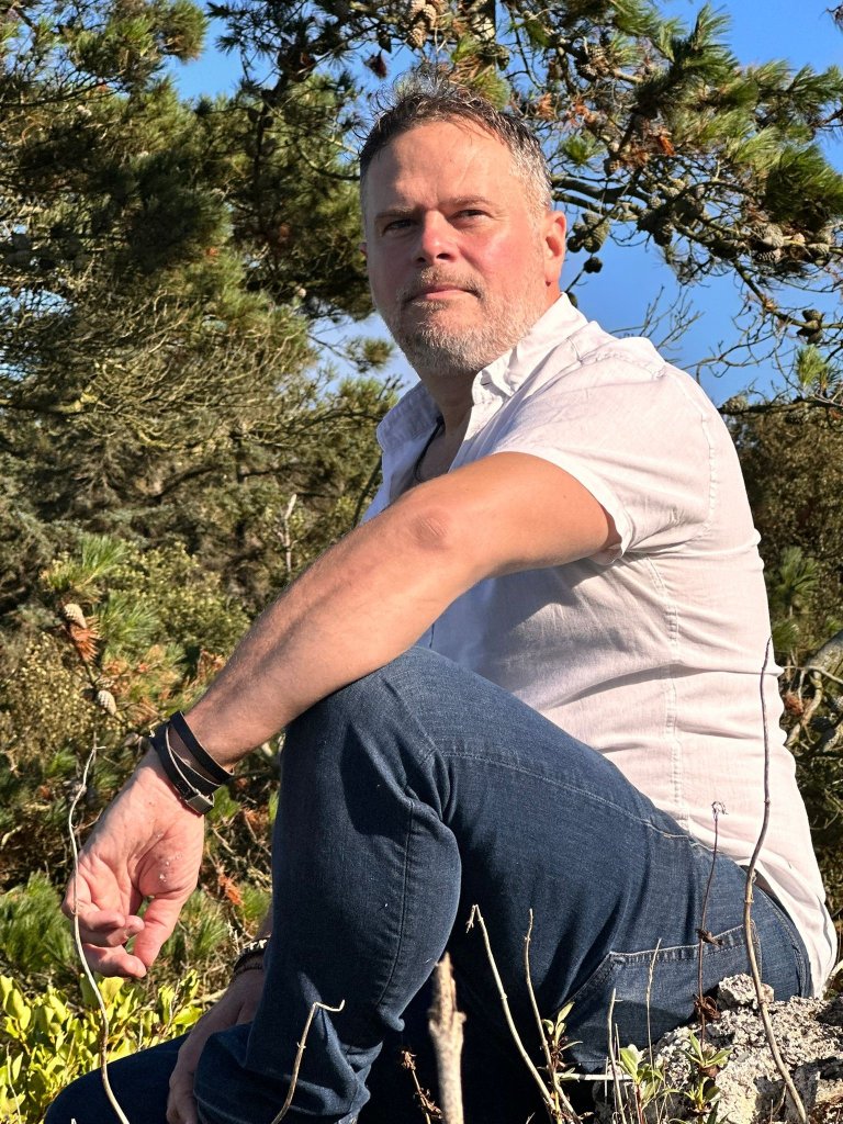 Garreth Falls, Medical Herbalist at The Wild Sage dispensary surrounded by herbal remedies and natural medicine