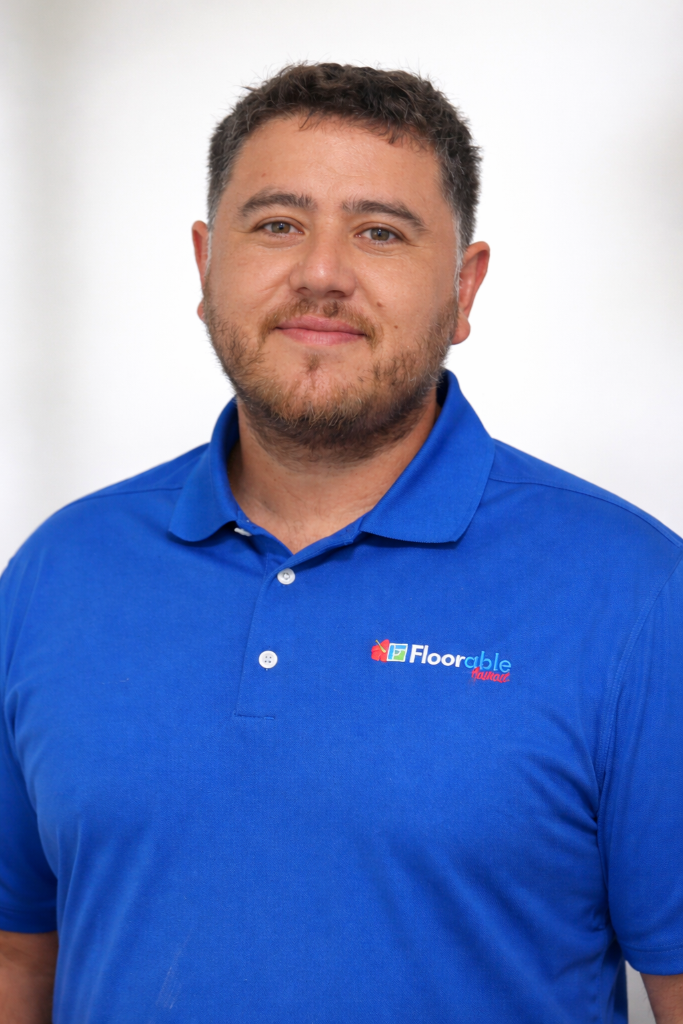 Man wearing a blue polo shirt with the Floorable Hawaii logo, smiling, representing the team behind premium flooring solutions in Maui.