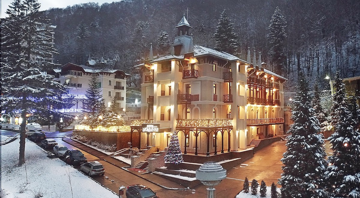 Hotel Moldavia în Slănic Moldova, clădire elegantă înconjurată de peisaje montane înghețate și brad de Crăciun.