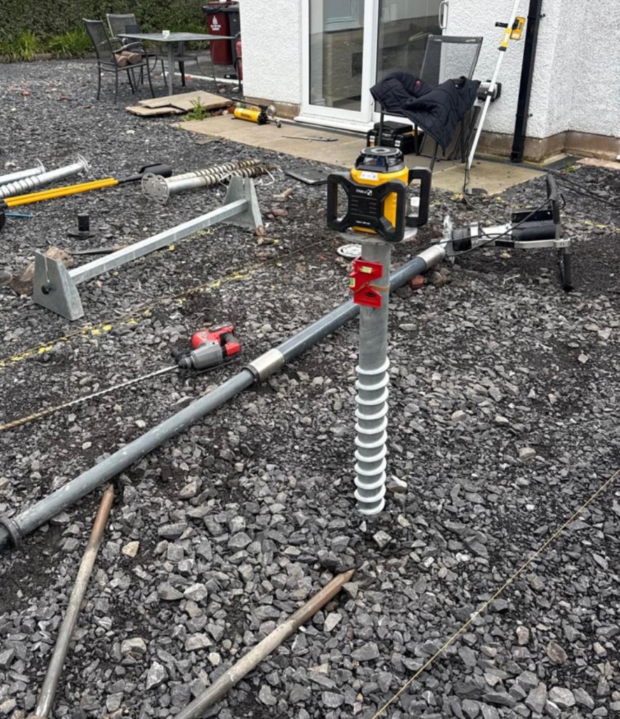 Ground screw installation equipment positioned over a foundation screw