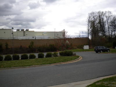Landscaped site with trimmed shrubs, grass, and concrete retaining wall alongside roadway at commercial development