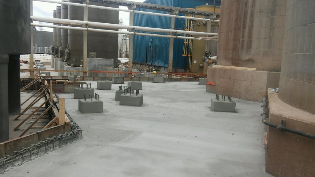 Industrial concrete foundation with anchor bolt assemblies for equipment mounting