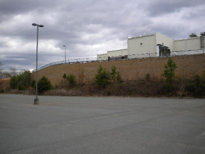 Interlocking stone block retaining wall with landscaped evergreens at commercial building