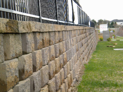 Retaining wall with vinyl fence installation along commercial property boundary