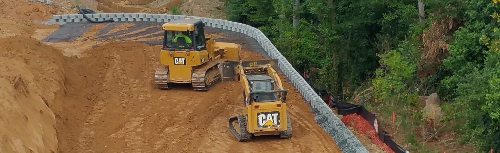 Heavy equipment building commercial retaining wall with CAT bulldozer and skid steer