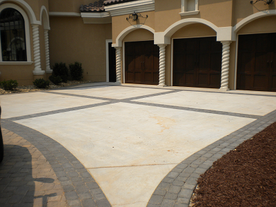 Residential concrete driveway with decorative paver border and accent banding