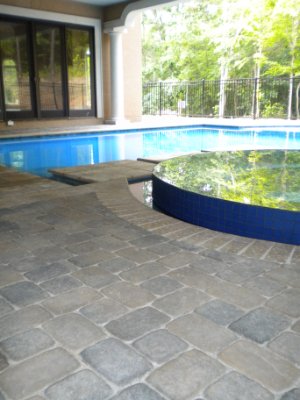 Paver pool surround installation with decorative border at residential backyard