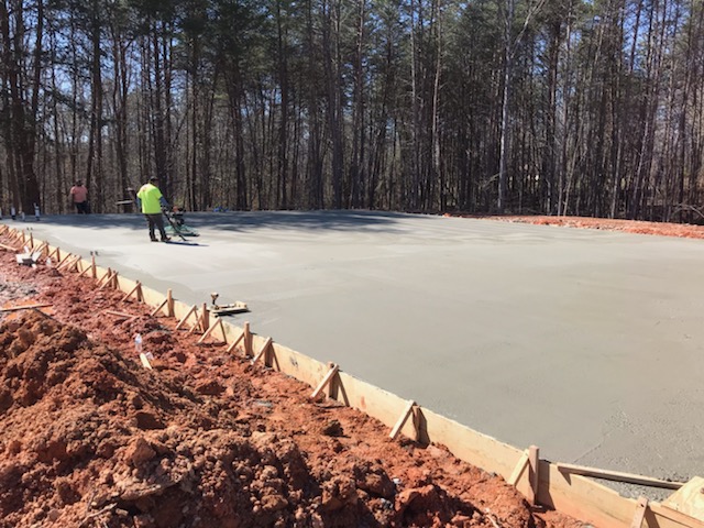 Worker finishing large concrete slab pour for utility substation foundation