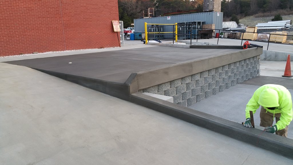 Commercial concrete loading pad with block retaining wall and smooth finish