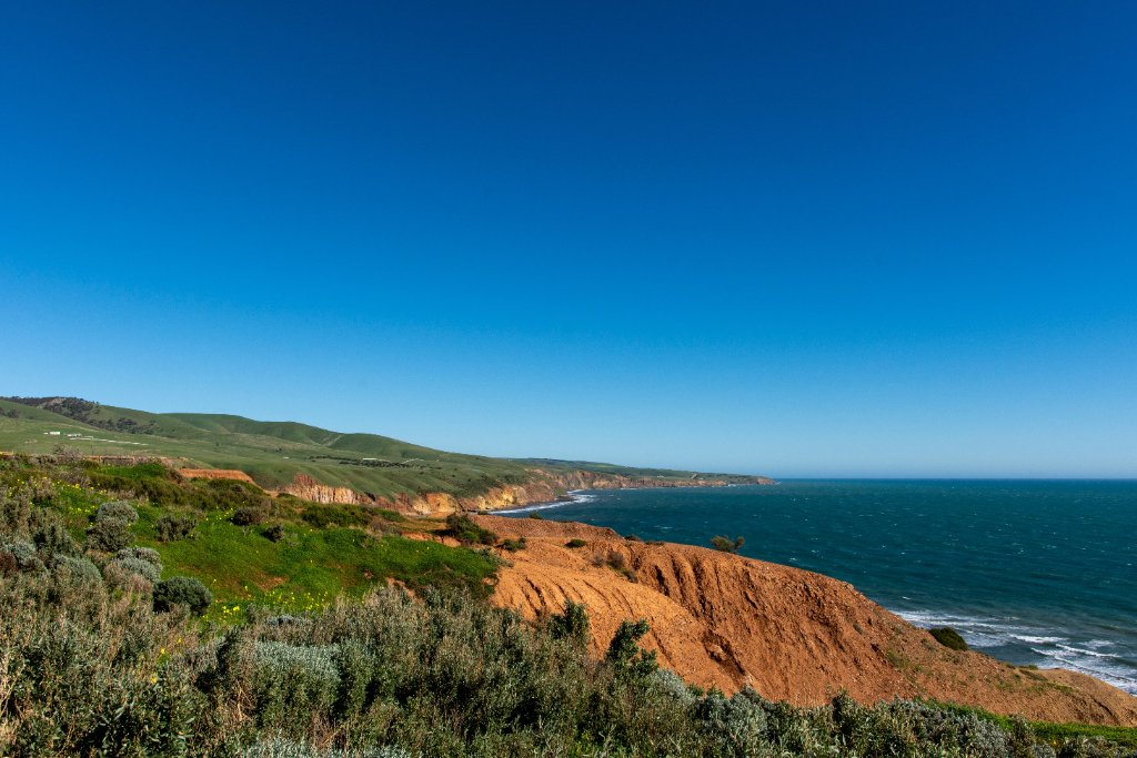 Stunning South Australian coastline with red cliffs, turquoise water and green hills — typical scenic Airbnb location on Fleurieu Peninsula requiring compliant fire evacuation diagrams