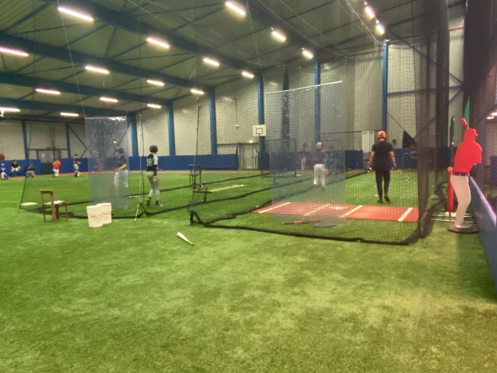 Indoor honkbalveld met netten en spelers