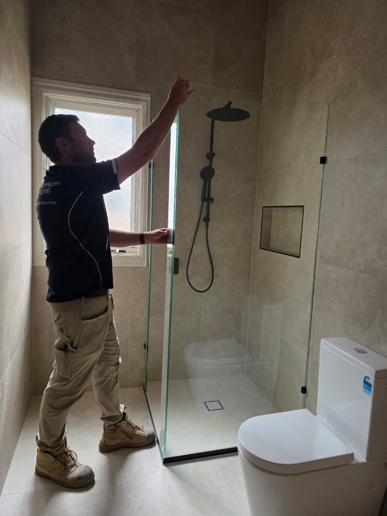 Brownlow Building tradesman installing a glass shower screen during a bathroom renovation