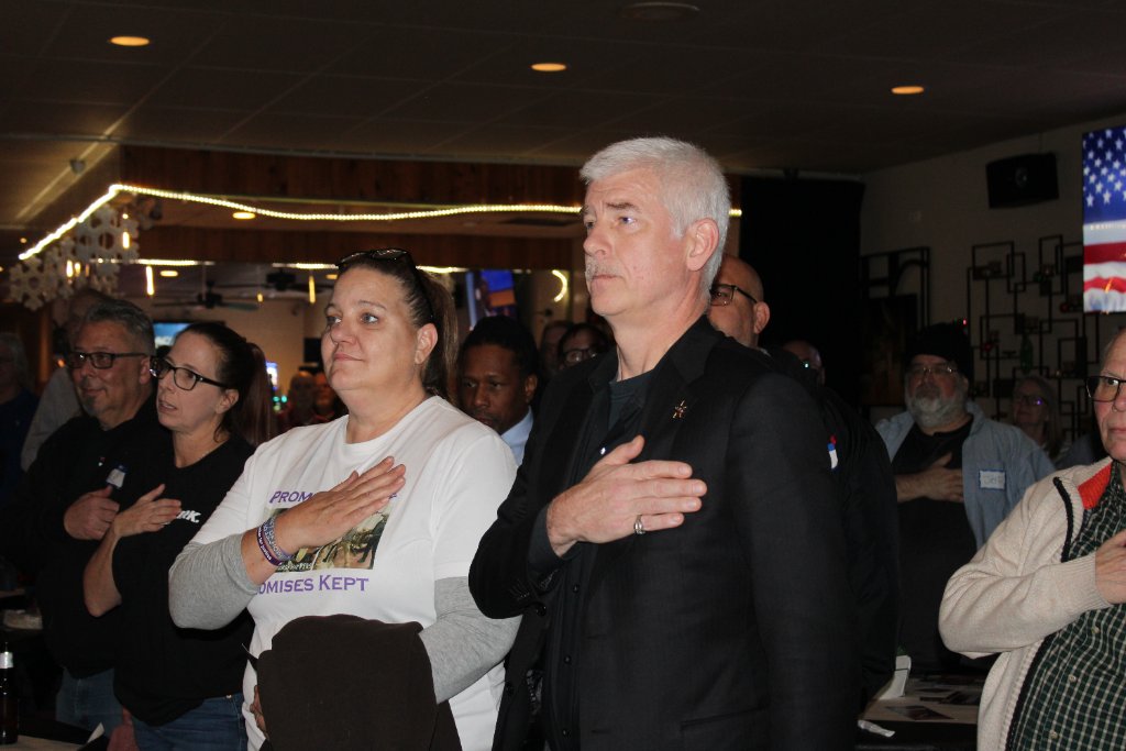 Attendees with hands over hearts during National Anthem