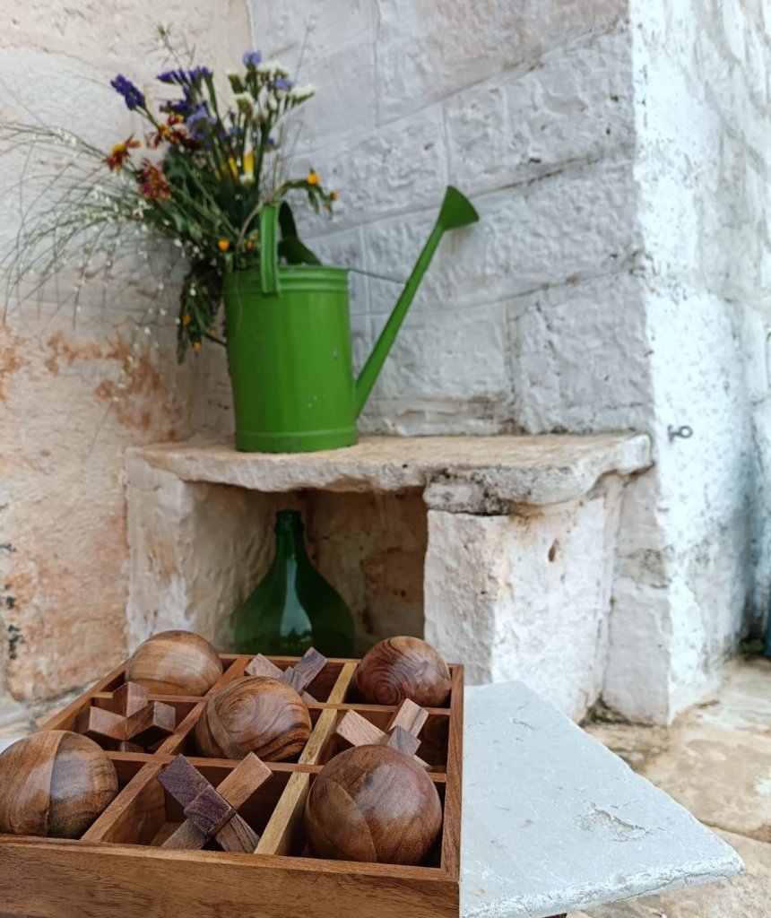 Green watering can and wooden spheres on ancient stone shelf