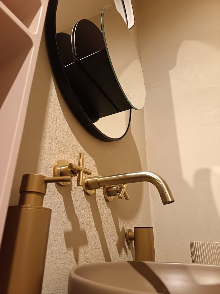 Bathroom with gold fixtures and designer mirror