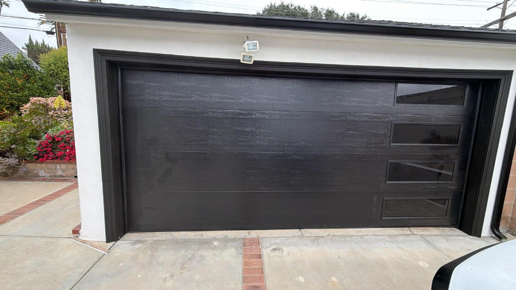 Contemporary black garage door featuring four offset horizontal glass window panels in modern architectural design