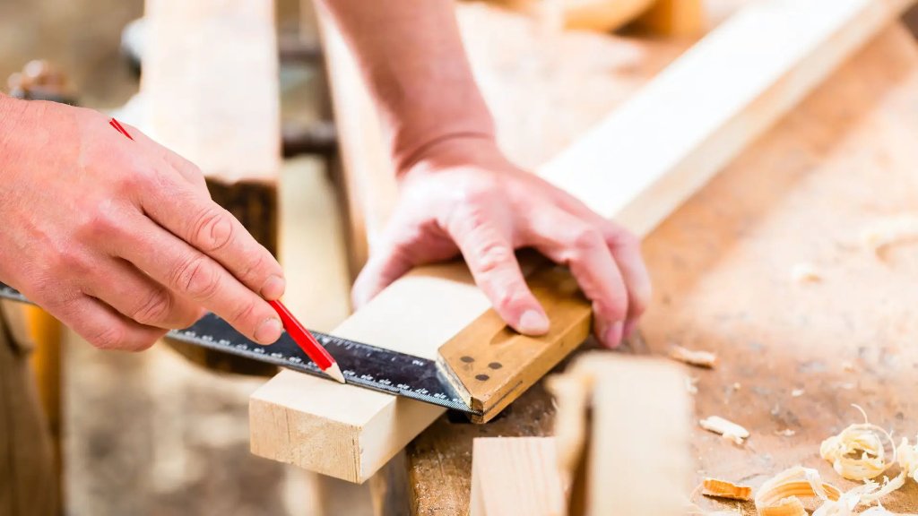 Professional carpenter measuring and marking wood trim