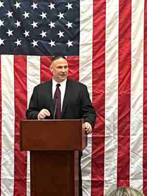 Roman Buchberger speaking at podium with American flag