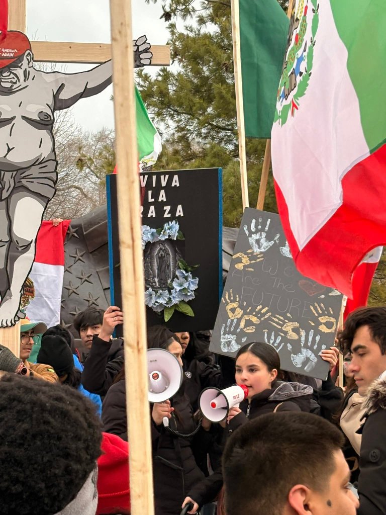 Students with megaphones and signs in a crowded protest scene