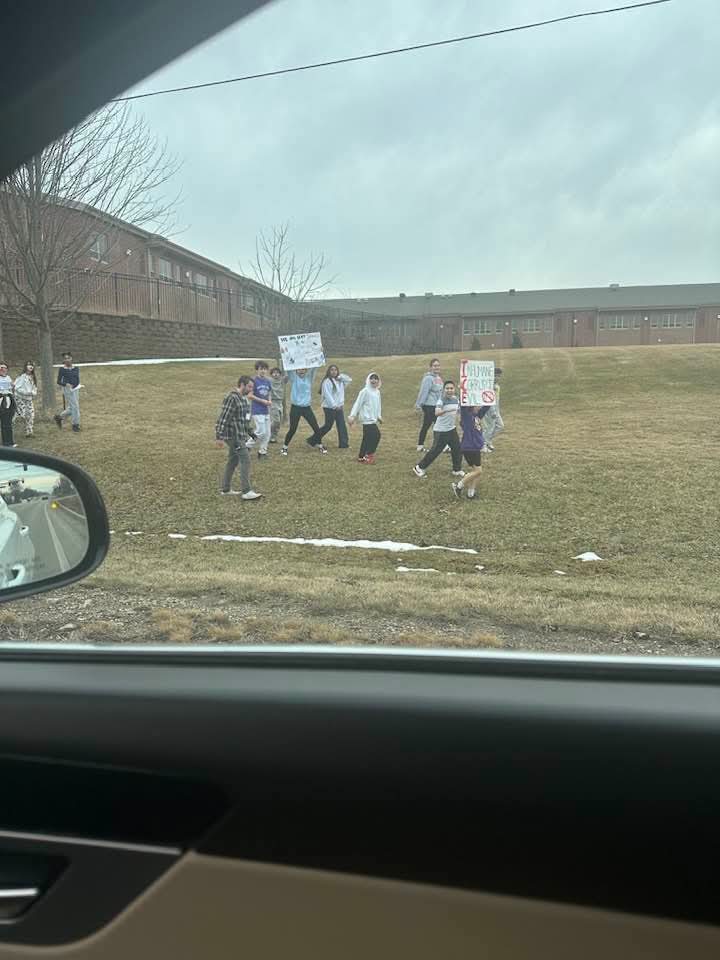 Middle school students with protest signs on school grounds