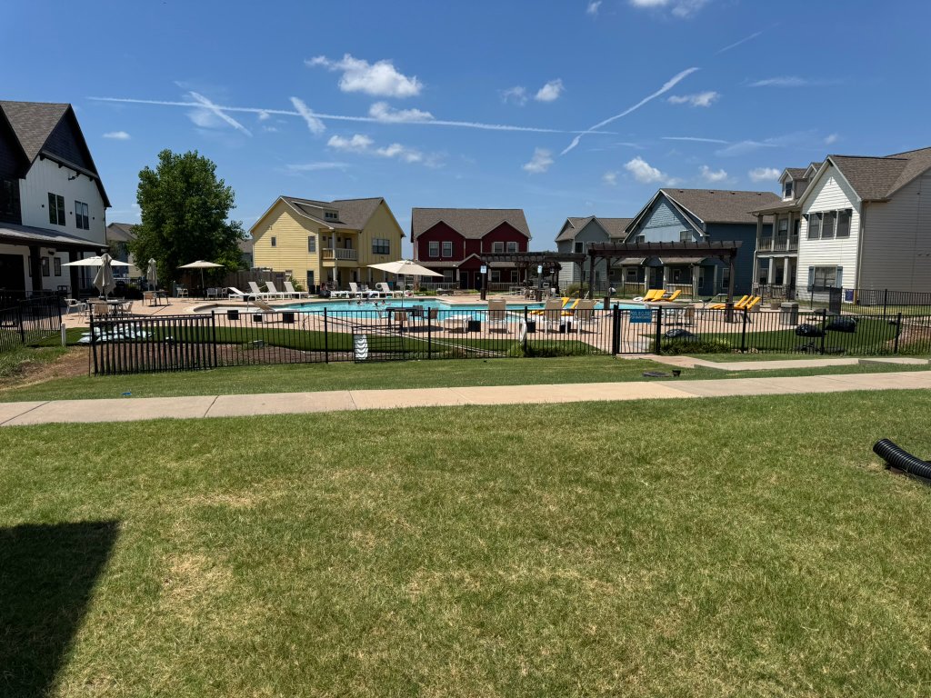 Natural-grass community lawn bordered by homes and fencing