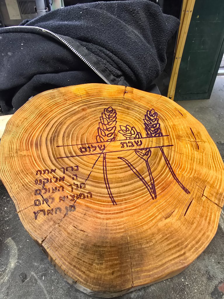 Round challah board with wheat and Hebrew text