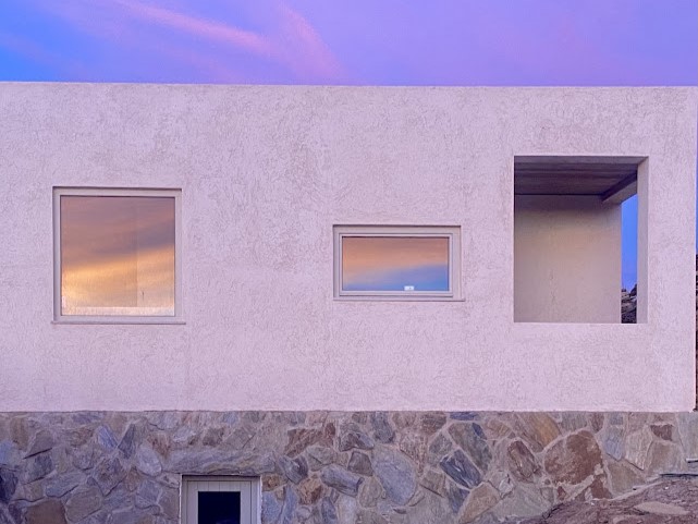 House facade with windows reflecting sunset sky