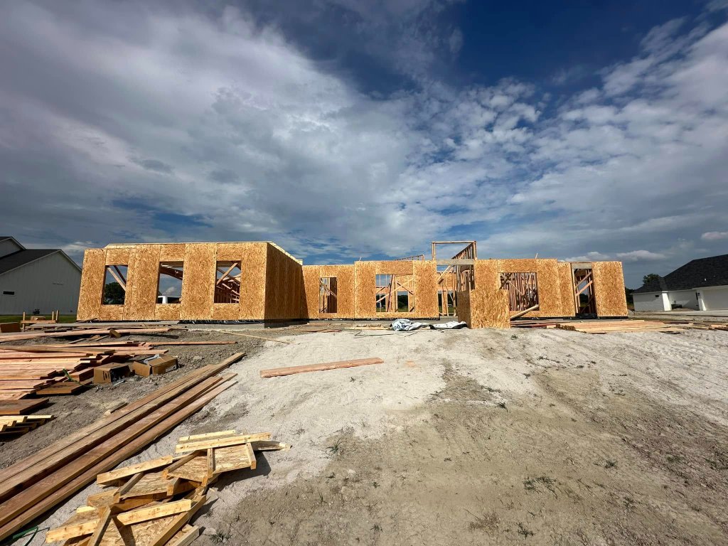 Framed walls of a new home under construction against a cloudy sky