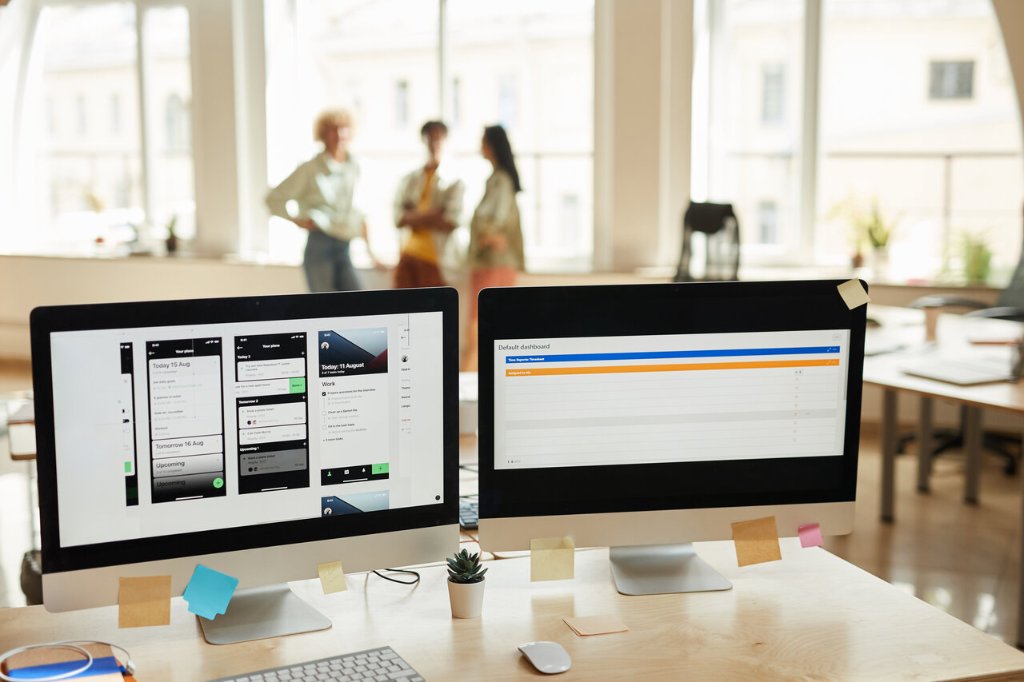 Computerskærme med kode og software i et professionelt kontormiljø