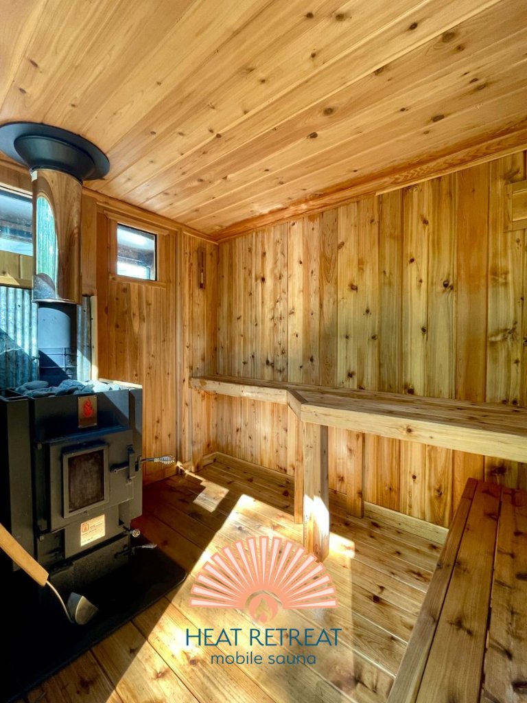 Inside WNY Heat Retreat mobile sauna — cedar interior with wood-burning stove