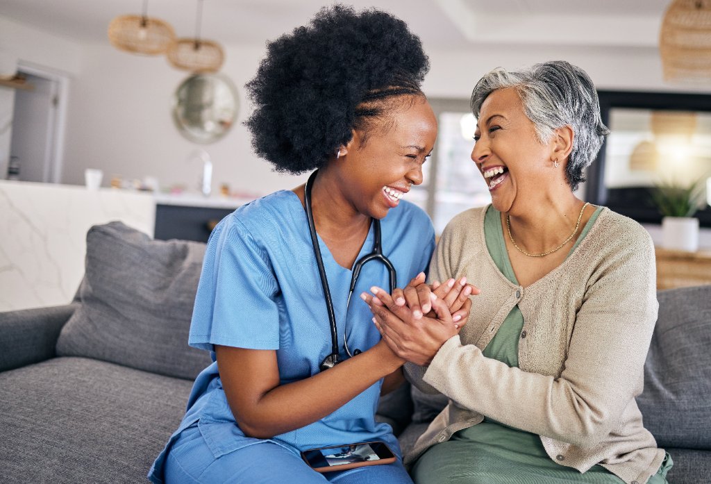 Elderly woman smiling with caregiver in home setting, representing professional in-home care in Rhode Island