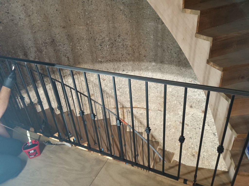 Custom curved black iron stair railing with decorative balusters being installed inside converted silo tower at the property, IL