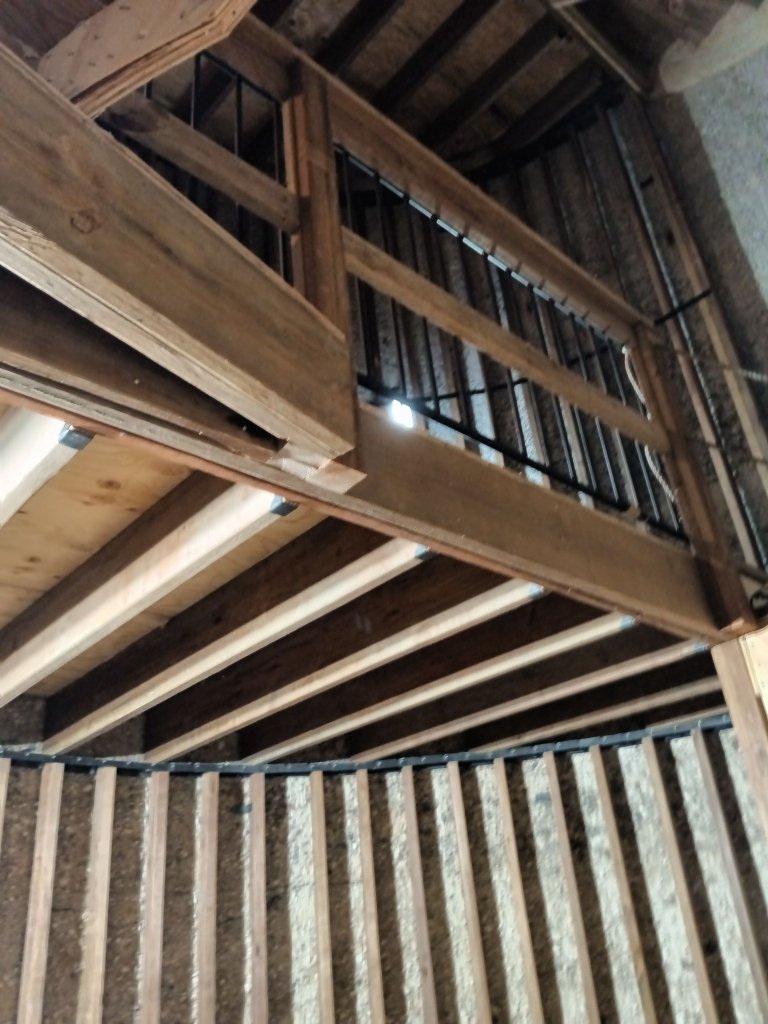 Custom iron loft railing with vertical balusters installed at upper level of converted silo tower interior, viewed from below