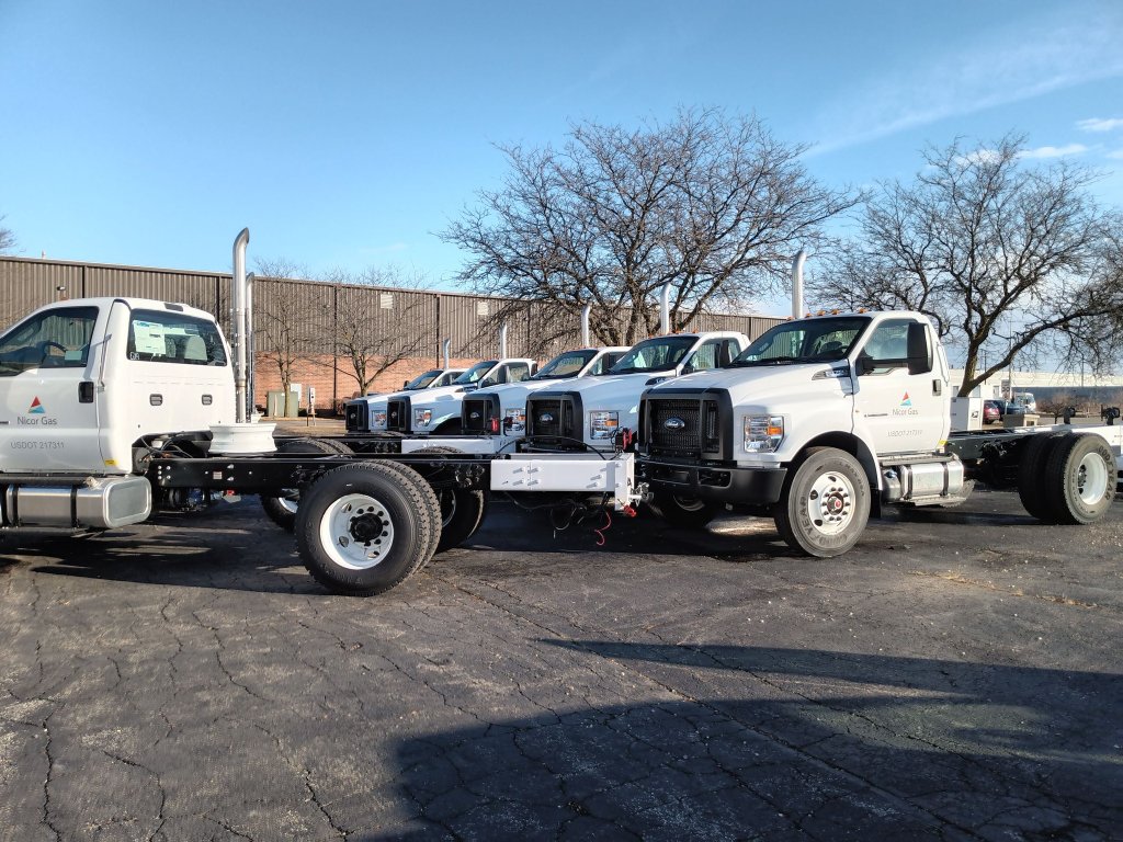 Front-angle view of commercial utility trucks with custom steel sub-frame chassis fabricated and installed