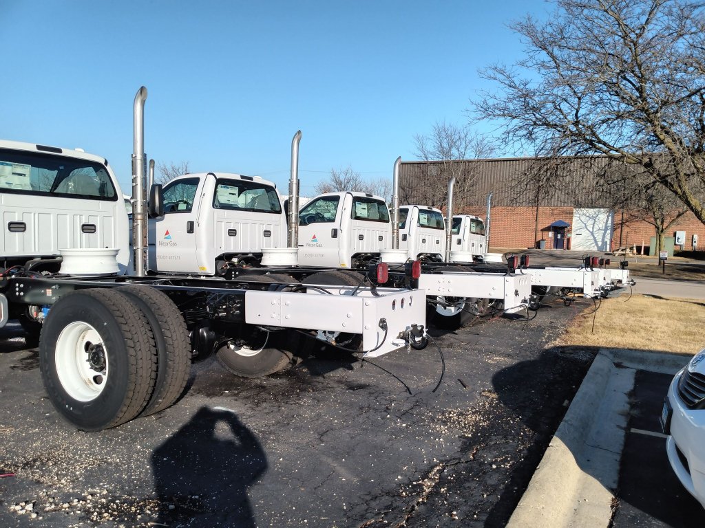 Fleet of commercial utility trucks with custom fabricated steel rear chassis sub-frames ready for body installation