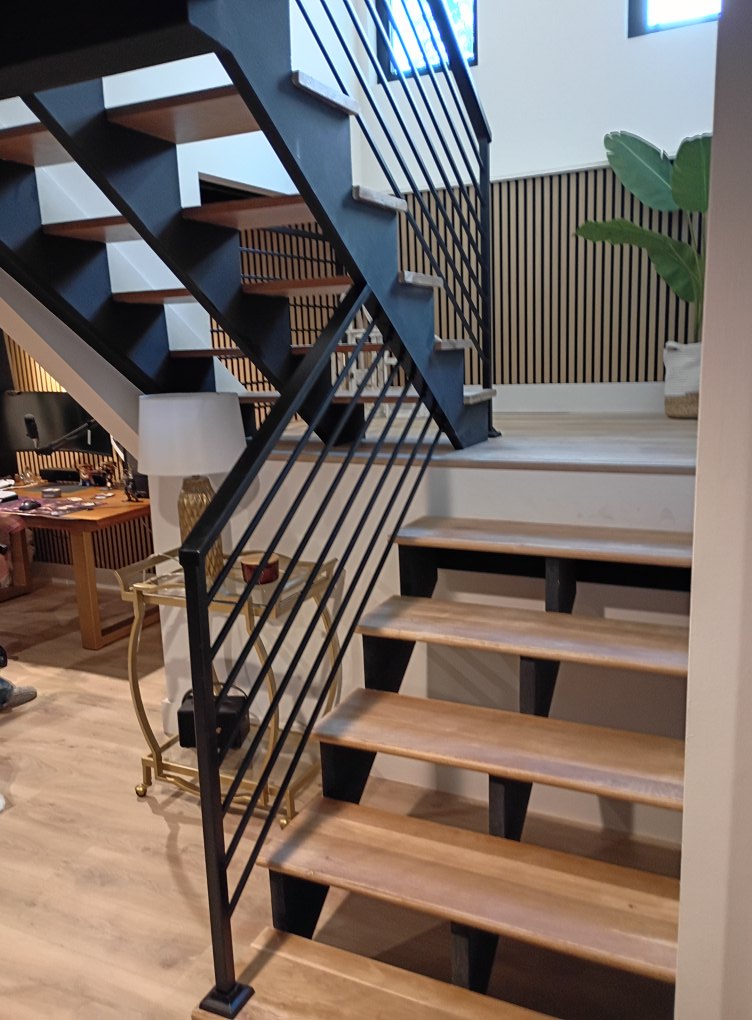 Custom black steel open-riser stair stringer with modern horizontal bar railing system installed in contemporary residential interior
