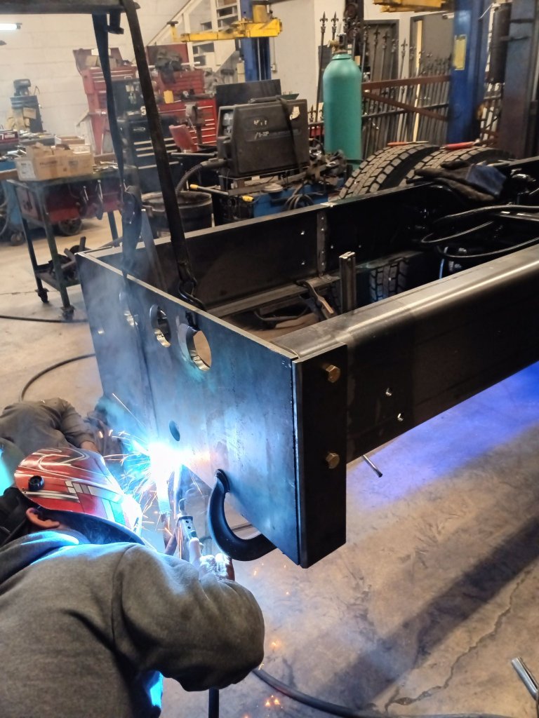 FOX Welding technician welding a tow hook onto a custom fabricated steel truck utility body with sparks visible in the West Chicago shop.