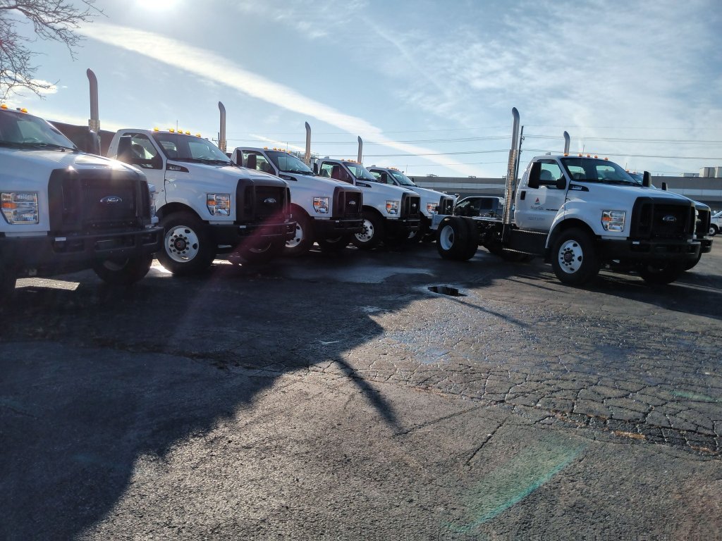Row of commercial trucks lined up with custom steel chassis and exhaust stack fabrication completed
