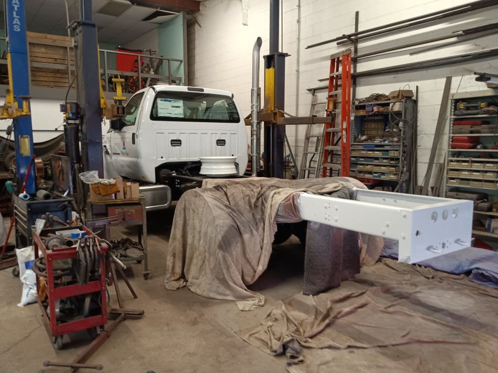 Custom fabricated white-painted steel utility truck body being prepared for mounting on commercial truck chassis in the shop
