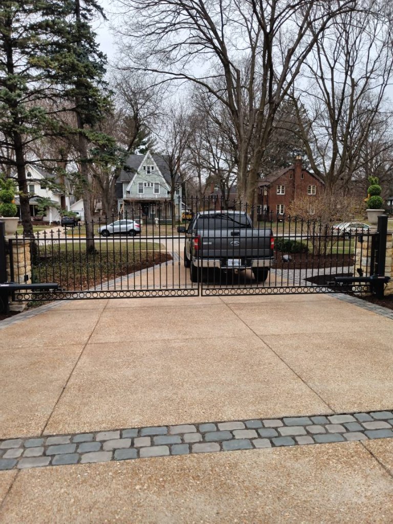 Custom ornamental iron double driveway gate with decorative scrollwork and spear-top finials installed at residential estate entrance, Fox Valley area IL