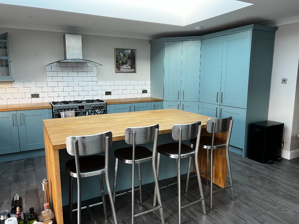 Professional kitchen cupboard spraying result showing smooth factory-finish in modern teal kitchen with wooden worktops