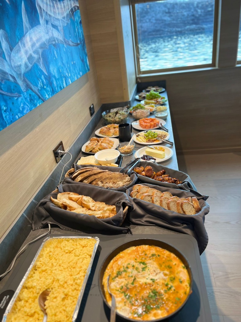 Yacht morning buffet with croissants, rolls, cheese platter and fresh fruit spread