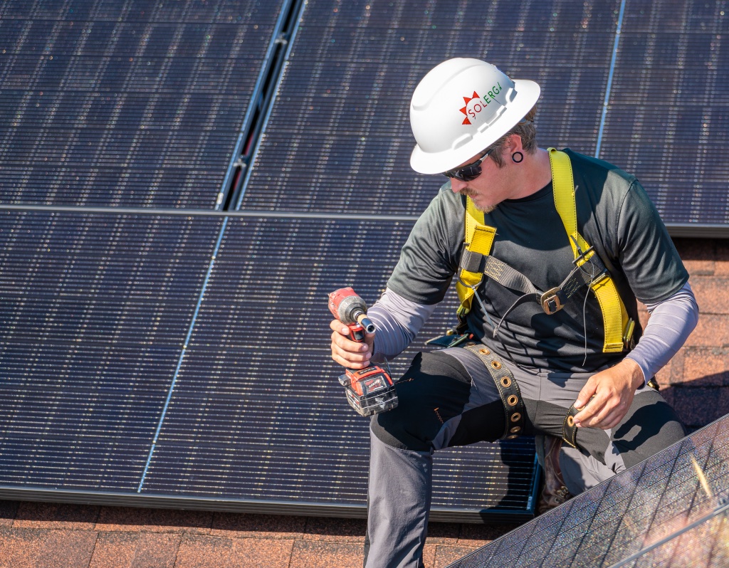 Solergy technician installing solar panels on rooftop
