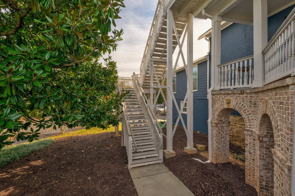 Exterior staircase with white railing leading to wraparound porches