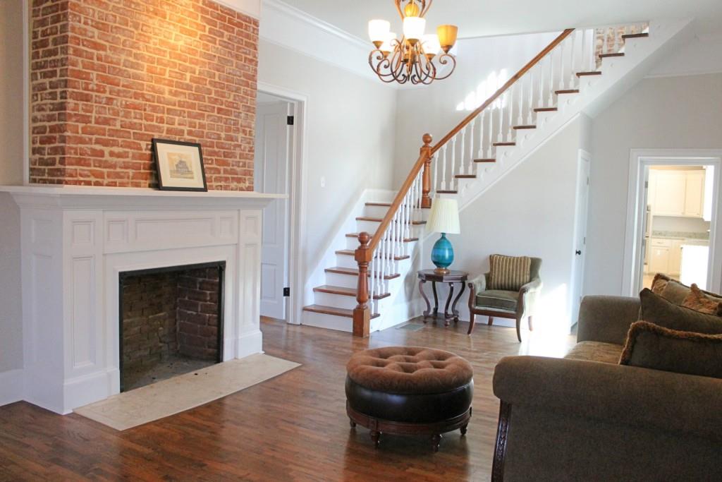 Elegant living room with exposed brick fireplace and vintage hardwood floors
