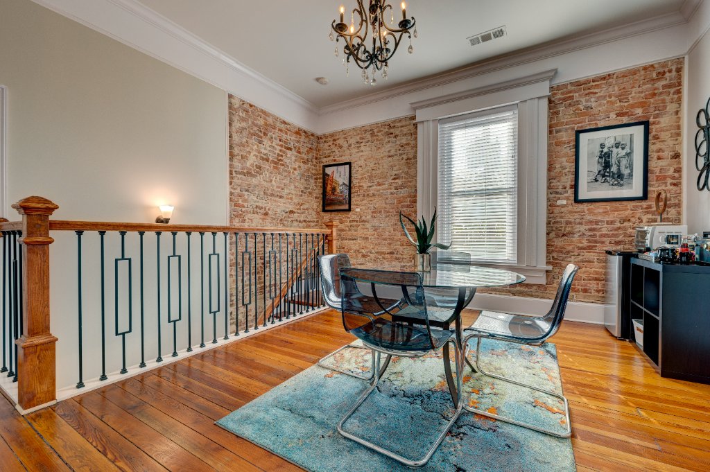 Second floor dining area with exposed brick walls and vintage hardwood floors
