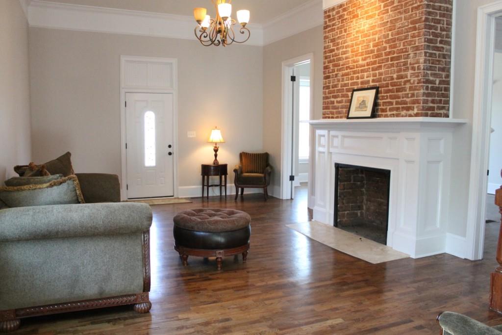 Living room with exposed brick fireplace and grand staircase