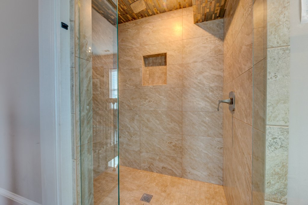 Luxury walk-in shower with marble tile and custom wood ceiling detail